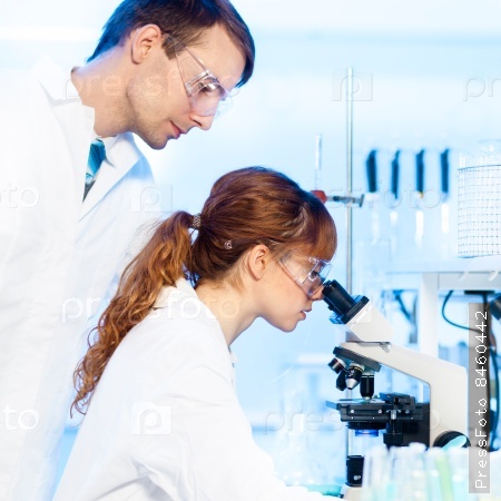Attractive young female research scientist and her post doctoral male supervisor looking at the microscope slide in the life science (forensics, microbiology, biochemistry, genetics, ) laboratory.