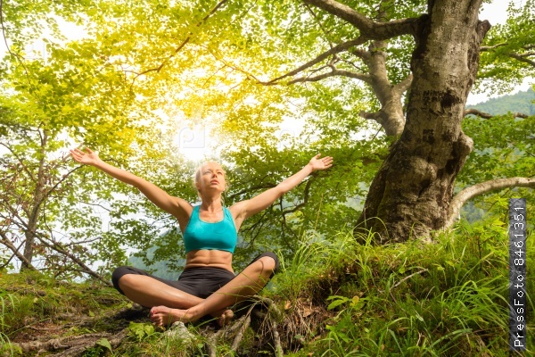 Relaxed woman enjoying freedom and life in beautiful natural environment. Blissful girl raising arms, feeling free, relaxed and happy. Concept of freedom, happiness, enjoyment and natural balance.