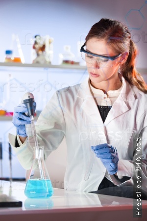 Life scientists researching in laboratory. Focused female life science professional pipetting blue solution into glass cuvette. Lens focus on researcher\'s eyes. Healthcare and biotechnology concept.