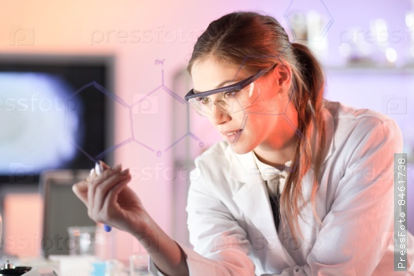 Life science researcher working in laboratory. Portrait of a confident female health care professional in his working environment reviewing structural chemical formula written on a glass board, stock photo
