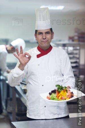 chef in hotel kitchen preparing and decorating food