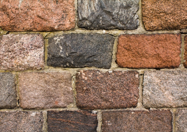 Part of a wall of a building combined from the present processed stones (not a brick)