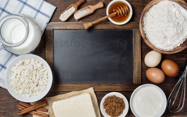 Ingredients for baking - milk, eggs, flour, cottage cheese, butter, sugar, sour cream. Rustic background with vintage blackboard with copyspace