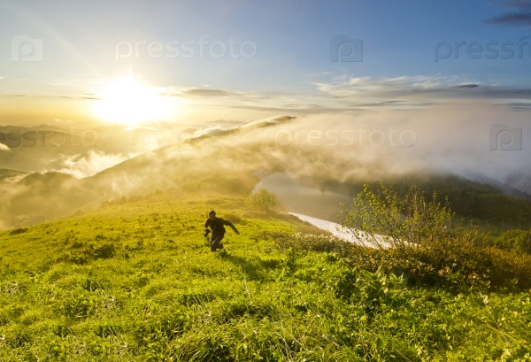 man running on a hill at sunset with camera