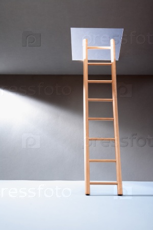 Escape concept. Wooden ladder in empty room with illuminated hatch in ceiling