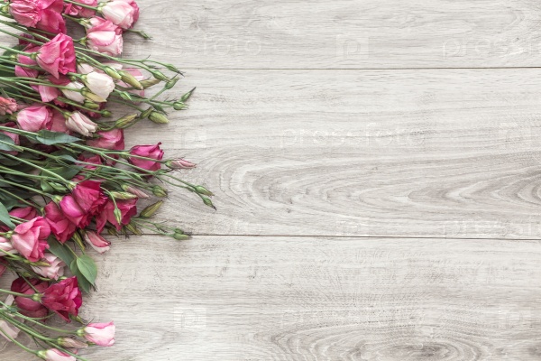 Pink eustoma flowers on natural wooden floor, selective focus, shabby chic style, space for custom text.