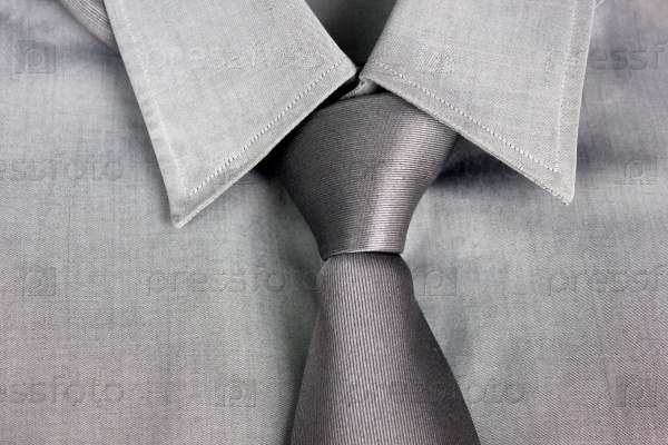Gray tie tied in knot round a collar of a gray shirt