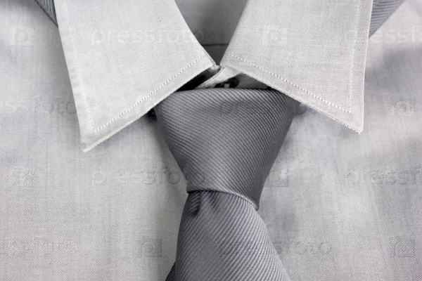 Gray tie tied in knot round a collar of a gray shirt
