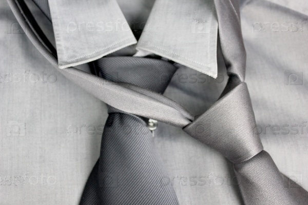 Two gray ties tied in knot round a collar of a gray shirt