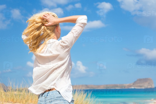 Relaxed woman enjoying freedom and life an a beautiful sandy beach.  Young lady feeling free, relaxed and happy. Concept of freedom, happiness, enjoyment and well being.  Enjoying Sun on Vacations.