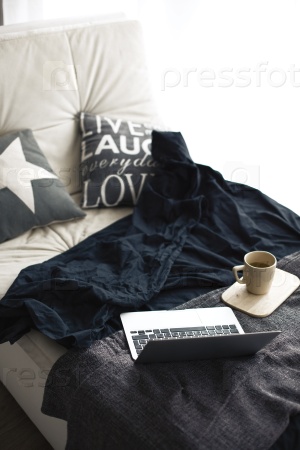 Cozy couch with blanket, coffee and laptop in black and white colors