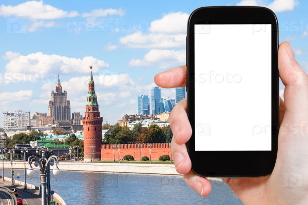 Travel concept - hand holds smartphone with cut out screen and Moscow landmarks on background, stock photo