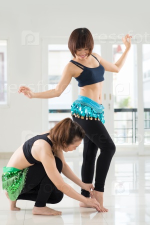 Belly dance instructor adjusting feet of young woman