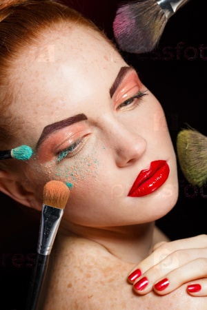 make up woman with makeup brushes.  Beautiful Face. Makeover. Perfect Skin. Applying Makeup. Make-up girl, woman teenager face with make up brushes and a blusher. Woman posing on black background
