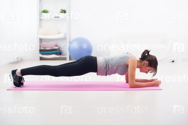 Stock Photo: Fit girl in plank position on mat at home the