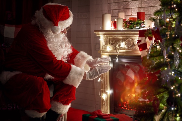 Santa Claus warming his hands at fire fireplace.