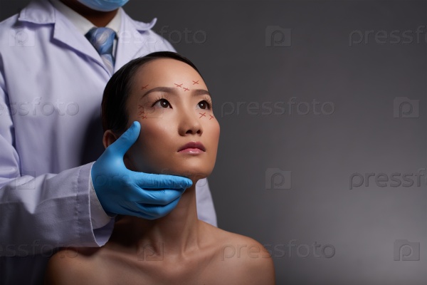 Beautiful woman with marks for future injections on her face