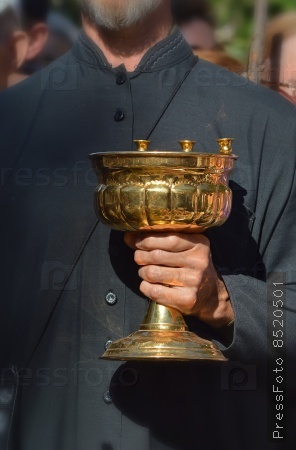 Водосвятная чаша со светильниками в руках церковного служащего перед обрядом освящения