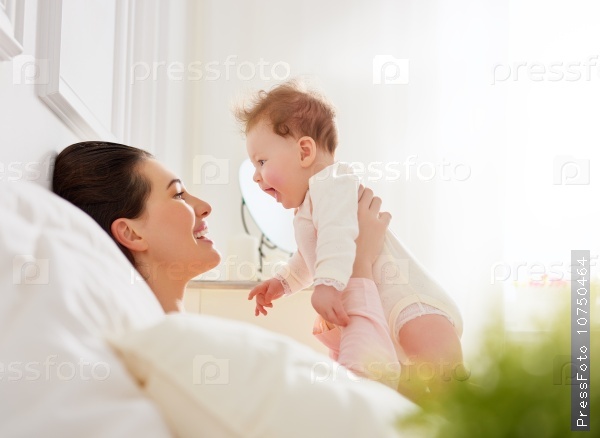happy family. mother playing with her baby in the bedroom.