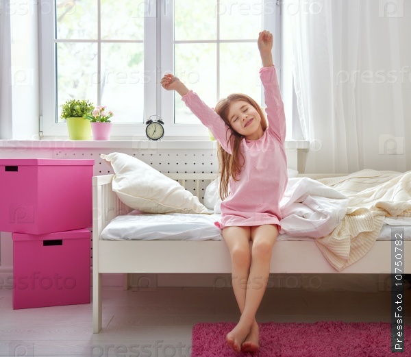 A nice child girl enjoys sunny morning. Good morning at home. Child girl wakes up from sleep.