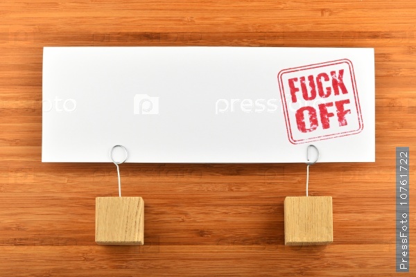 Fuck off red rude stamp on one big white paper note with two wooden holders on wooden bamboo background for presentation, stock photo