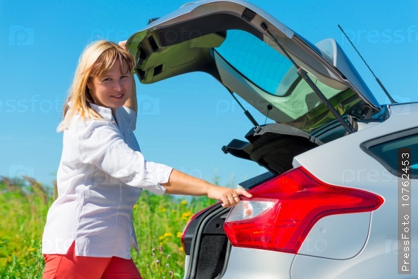 Woman closes the trunk of the car type hatchback, stock photo