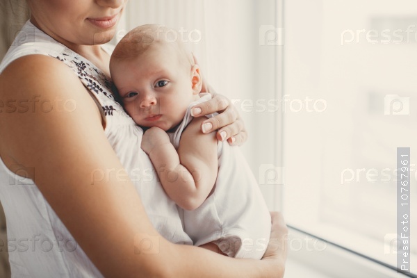 Portrait of a mother with her 3 months old baby. Mother holding head of her newborn son in hands. The baby on hands at mum. Loving mother hand holding cute sleeping newborn baby.home portrait. love