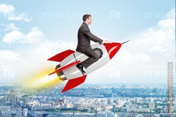 Businessman flying on drawn rocket above cityscape, stock photo