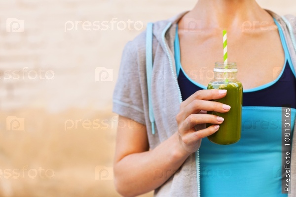 Woman drinking vegetable smoothie after fitness running workout on summer day. Fitness and healthy lifestyle concept