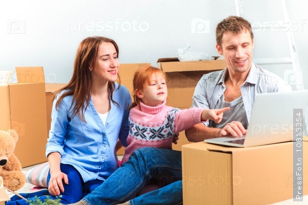 The happy family with laptop at repair and relocation on a background of boxes, stock photo