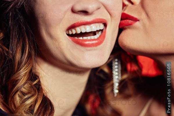 Close-up of woman laughing while other girl kissing her, stock photo