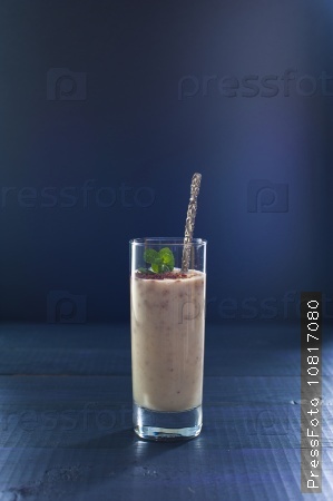 Glass of banana smoothie on wooden background