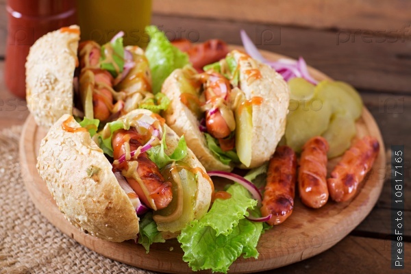 Hot dog - sandwich with pickles, red onions and lettuce on wooden background, stock photo