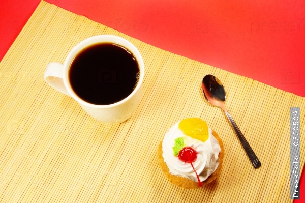 cup of coffee and fruit cake on bamboo on red background
