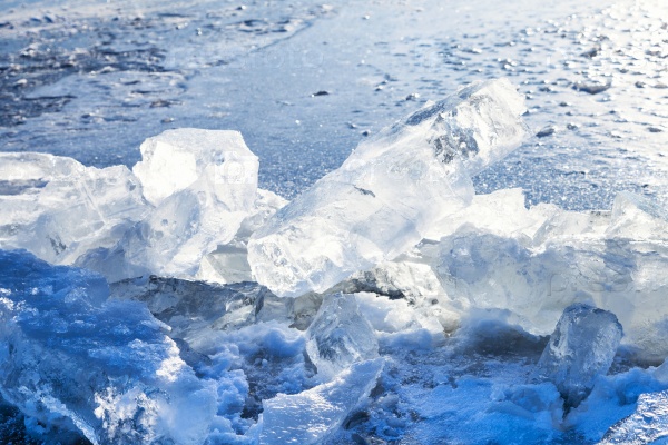 Ice blocks illuminated by sun on the edge of clearing in frozen river in cold winter day, stock photo