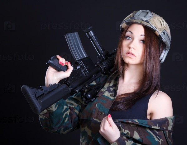 Portrait of a woman in a military uniform with an assault rifle over black background