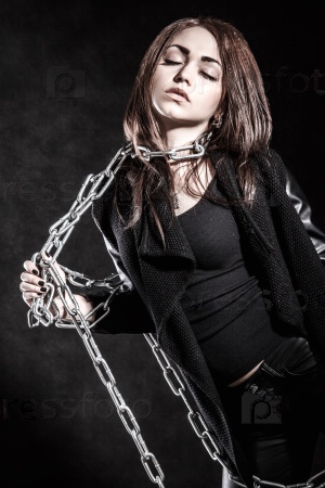 Young woman in a black clothes with a chain over dark background