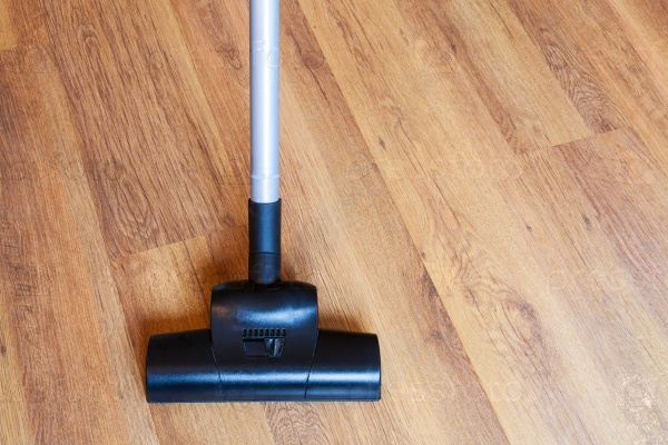 Direct view of vacuuming of laminate floor by vacuum cleaner at home, stock photo