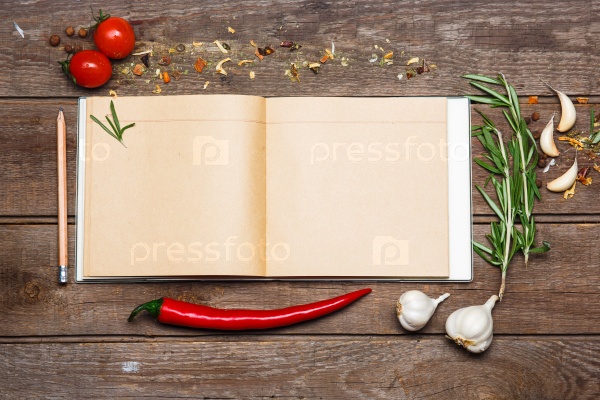 Open blank recipe book on brown wooden background with tomatoes, garlic, red hot peppers, stock photo