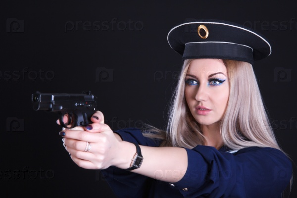 Woman in a navy uniform with a gun over black background