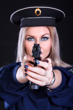 Beautiful young woman in a marine uniform with a gun over black background (focus is on the gun)