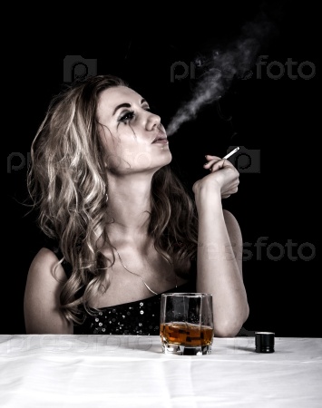 Depressed young woman with a glass of whiskey and a cigarette over black background