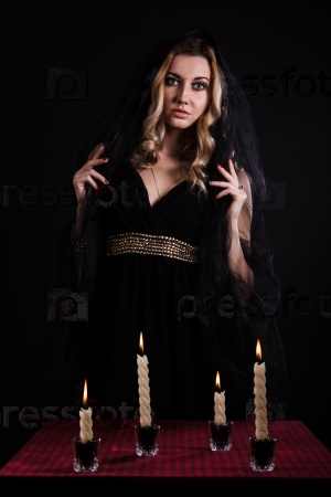 Mysterious young woman with candles in darkness