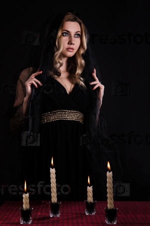 Mysterious young woman with candles in darkness