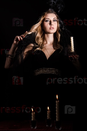 Scared young woman with a candle in darkness