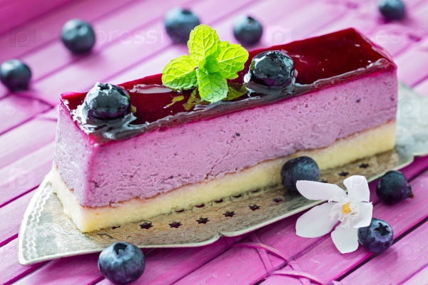 Slice of blueberry mouse cake with mint lraf on old antique cake slicer , stock photo