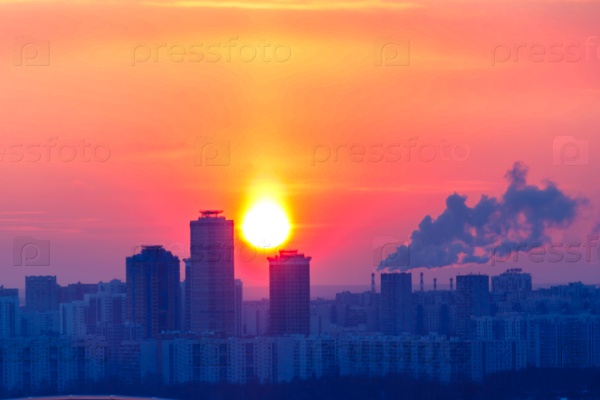 Frosty evening in Moscow, the sun is setting behind high-rise buildings, from the chimneys smoke, stock photo