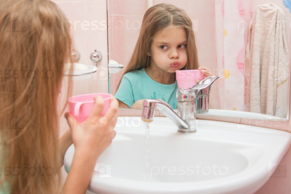 Six year old girl washes and brushes his teeth in the bathroom, stock photo