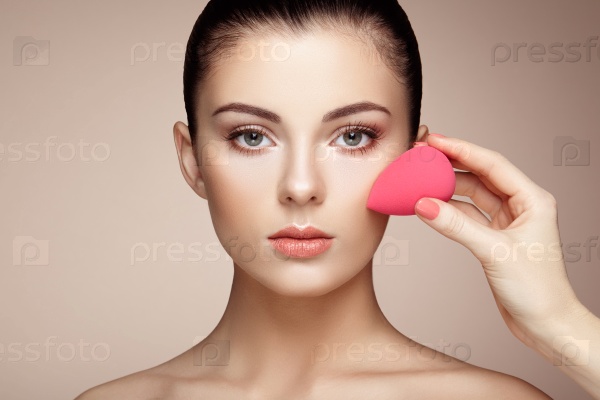 Makeup artist applies skintone. Beautiful woman face. Perfect makeup. Skincare foundation. Sponge makeup artist, stock photo