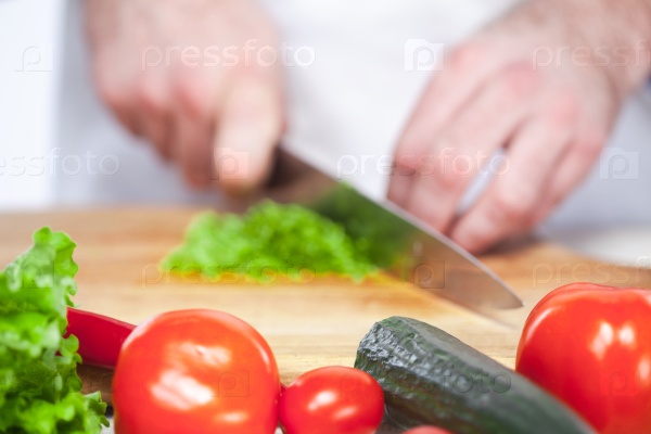 The hands of chef cutting a green lettuce in his kitchen on white background , stock photo